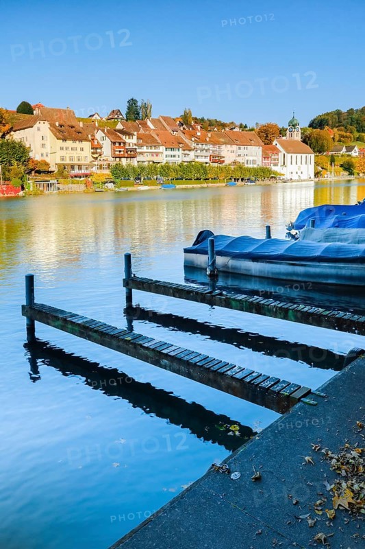 View from the banks of the Rhine over the Rhine towards the old town of Eglisau with reflection on the river water