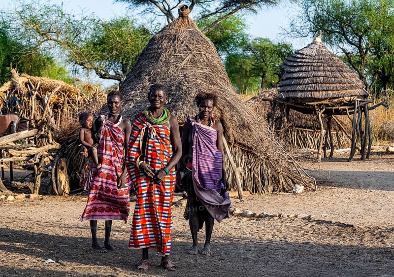 Older women from the Toposa tribe before their traditional hut
