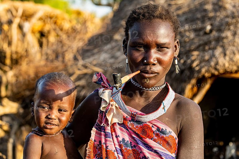 Woman from the Toposa tribe with her baby smoking a pipe