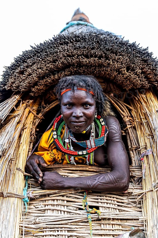 Traditional dressed girl from the Toposa tribe sitting in a grain storage