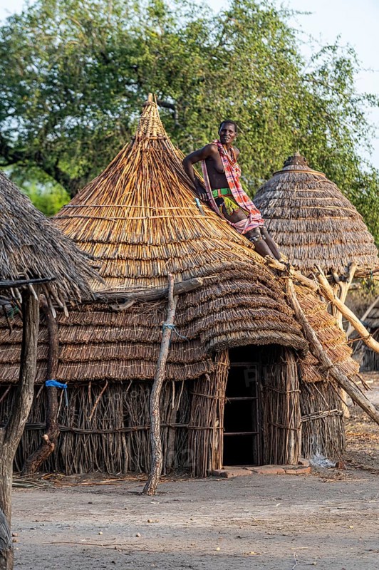 Woman repairing a roof of a traditional build hut of the Toposa tribe