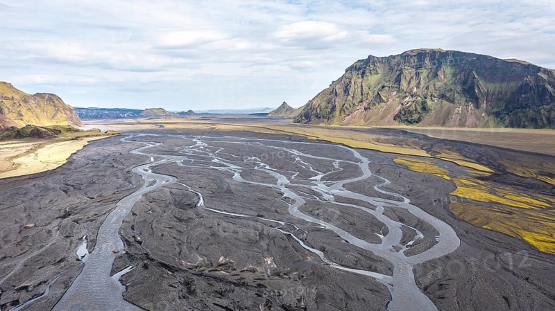 River with fanned out branches through black lava sand