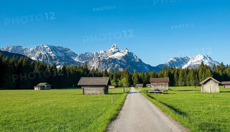 Road through meadow with hay barns
