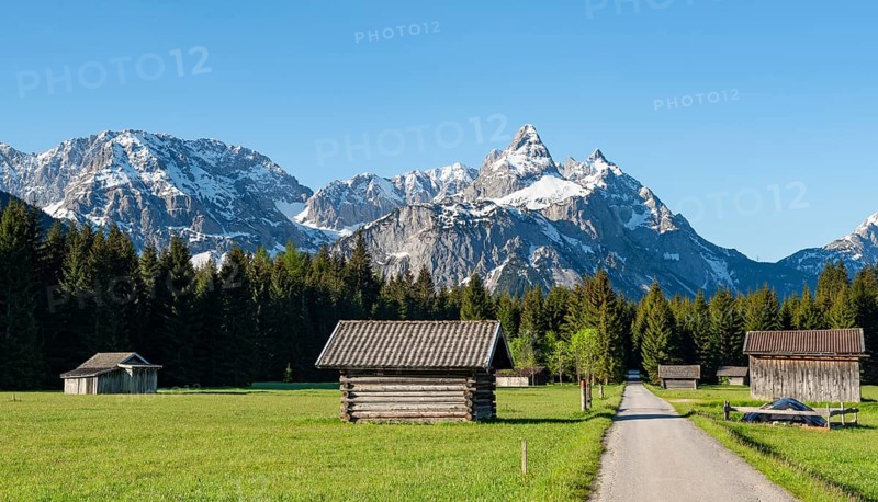 Road through meadow with hay barns