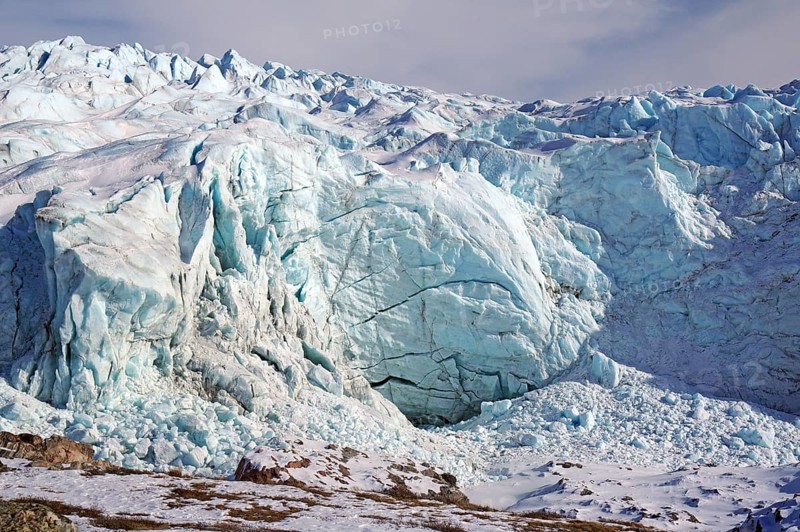 Large ice front of a glacier with crevasses and cracks