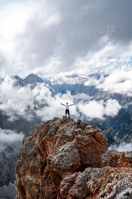 Hiker on a rock stretches arms in the air