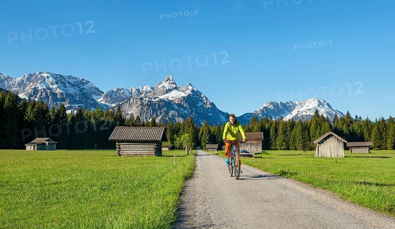 Mountain biker on road through meadow with hay barns