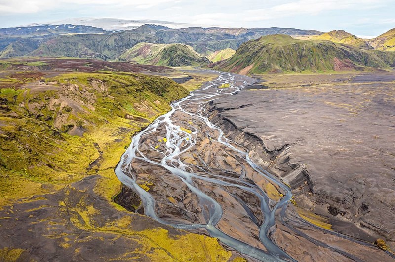 River with fanned out branches through black lava sand