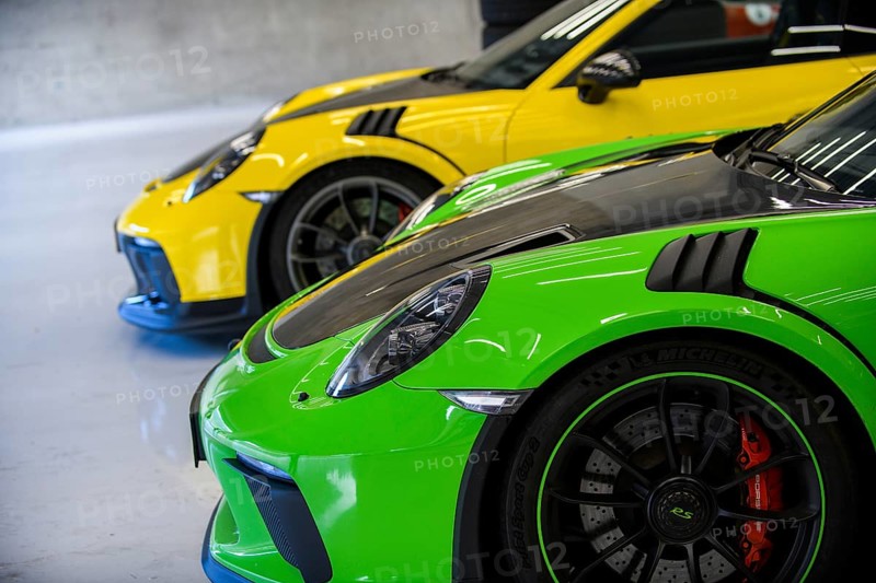 Side view of front with round headlights and rim of Porsche 911 GT3 RS race car in pitbox