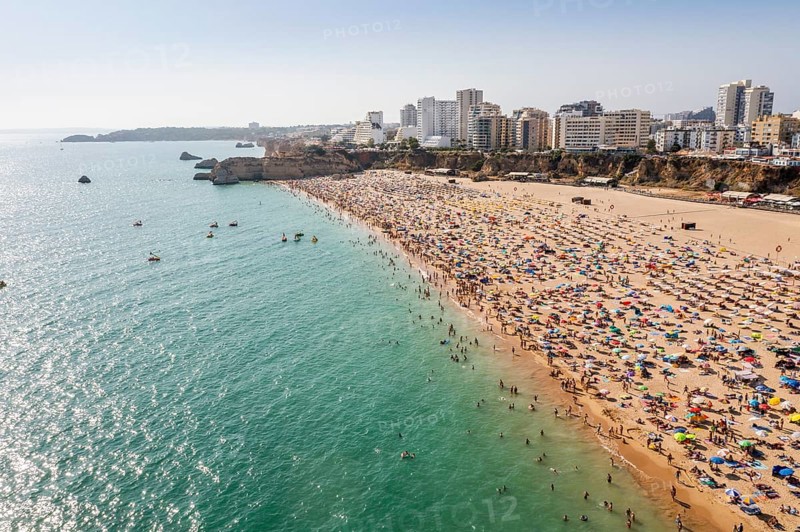 Aerial view of touristic Portimao with wide sandy beach Rocha full of people