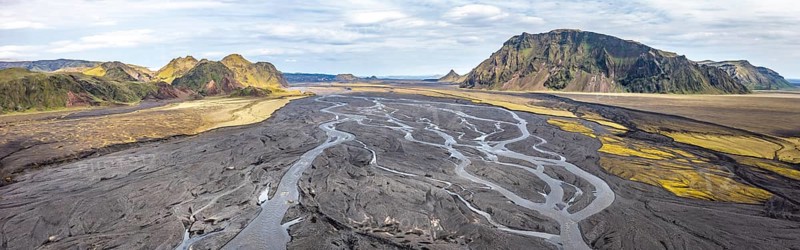 River with fanned out branches through black lava sand