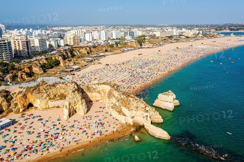 Aerial view of touristic Portimao with wide sandy beach Rocha full of people