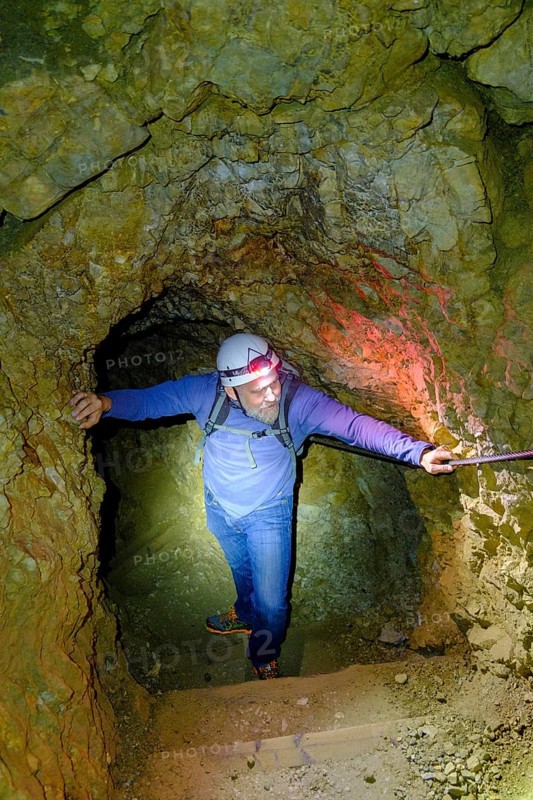 Climber with helmet and headlamp in rock tunnel