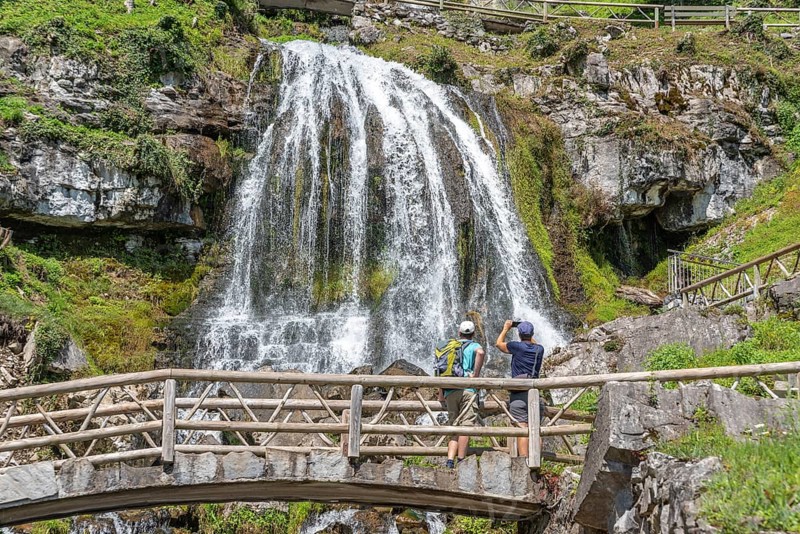 Hikers at the waterfall in front of the Saint Beatus Caves