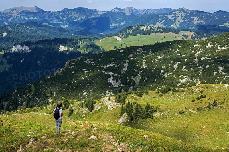 Hiker looking north from the hiking trail Obere Gottesackerwaende towards the Allgaeu Alps