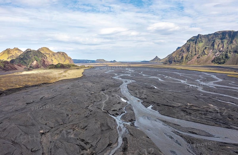 River with fanned out branches through black lava sand