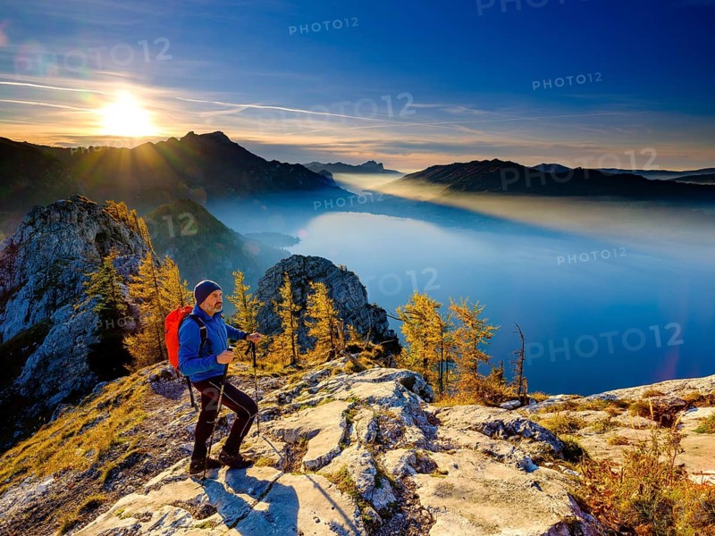 Mountaineer climbing the large Schoberstein in the evening light with view of Attersee and Mondsee
