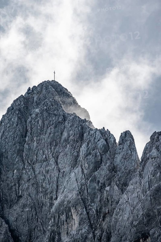 Rocky summit with summit cross between clouds