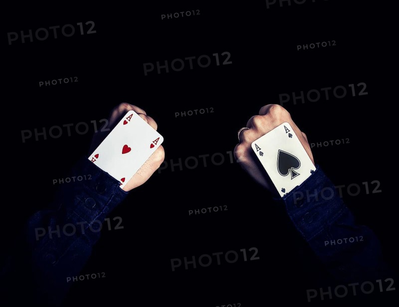 Two fists with hearts and spades aces in the hole