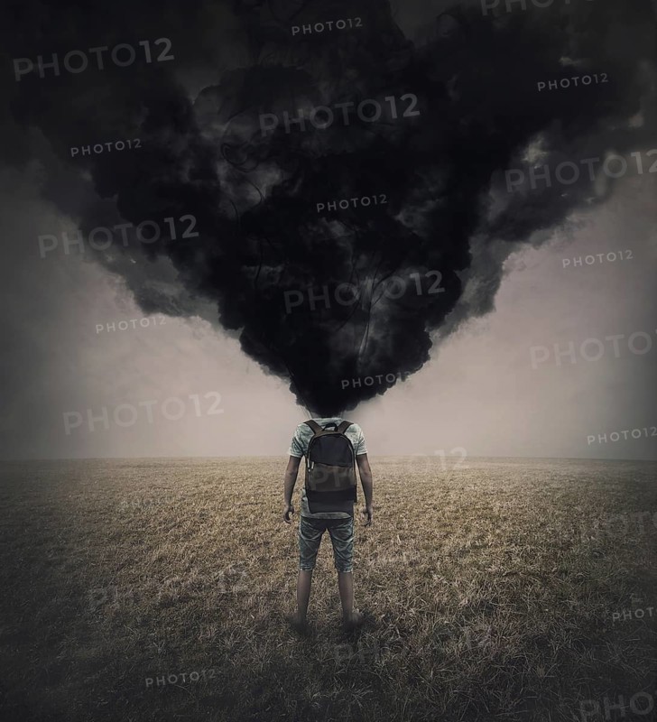 Surreal scene of a lone man in the field with dense black smoke instead his head