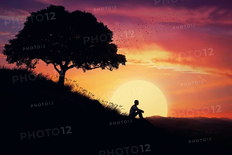 Boy sit alone on a hill in the center of nature