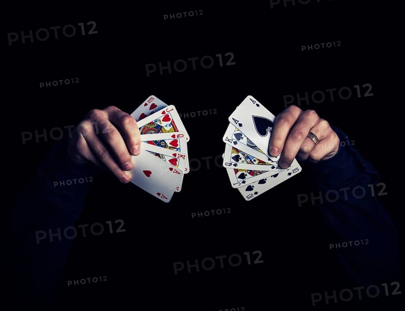 Man's hands holding five playing cards each over
