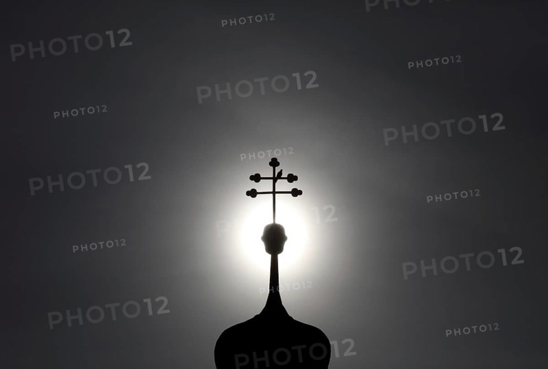 Double cross with dove on a church tower in backlight