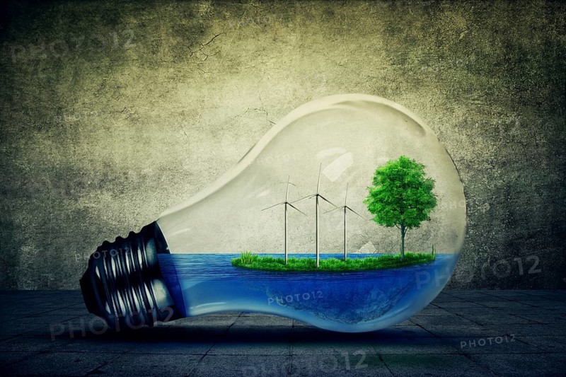 Light bulb as a micro planet with blue water and a island with green grass and tree growing inside