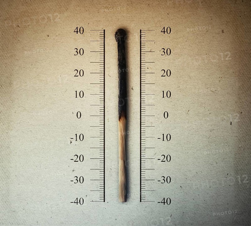 Burned match indicating temperature on a scale as a thermometer