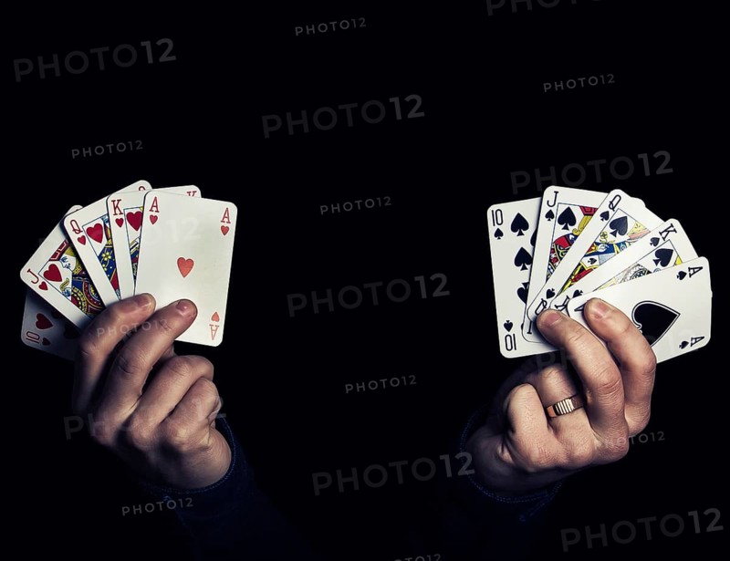 Caucasian male hands holding two royal flush poker combination of heart and spade