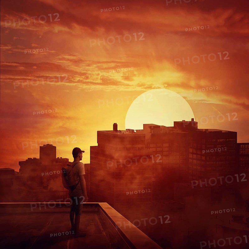 Young boy stay on the rooftop looking at the sunset