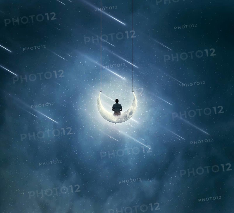 Surreal background with a boy sitting on a crescent moon
