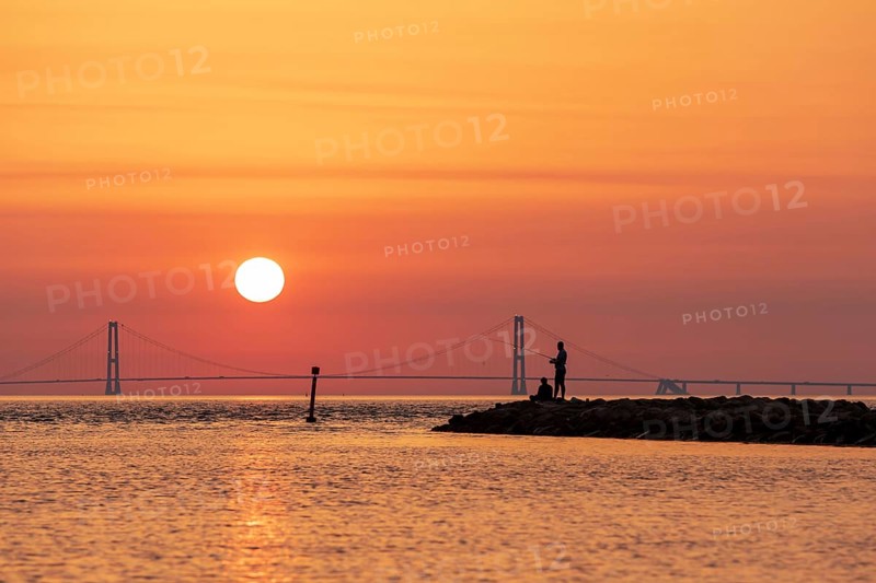 Silhouette of two men fishing with the Great Belt Bridge in the background