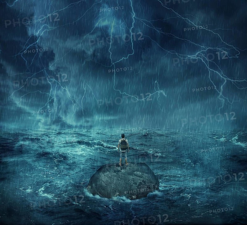 Lost man standing abandoned on a rock island in middle of the ocean