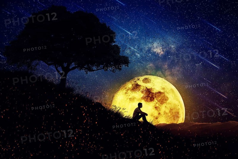 Boy sit alone on a hill in the center of nature