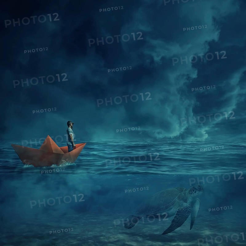 Young boy in a orange paper boat sail lost in the ocean