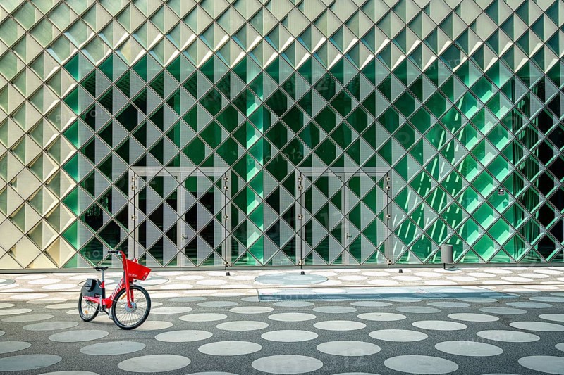 Red rental bike standing in front of the glass facade of the Futurium Museum on Kapelle Ufer