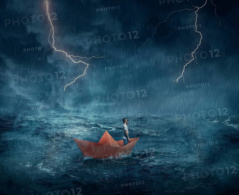 Young boy in a orange paper boat sail lost in the ocean