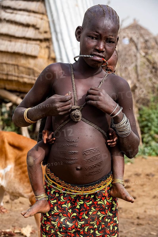 Scar face and body as a mark of beauty woman from the Jiye tribe sitting in her hut