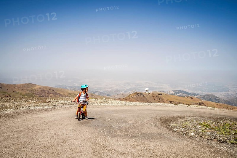 Small boy riding uphill on his first bicycle in Sierra Nevada mountains