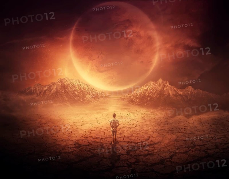 Surreal background as a young boy walks on another planet with dry and cracked ground