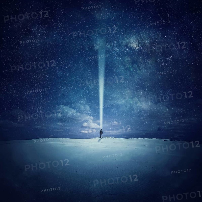 Milky Way night sky with stars and silhouette of a standing alone man in the middle of a sandy desert