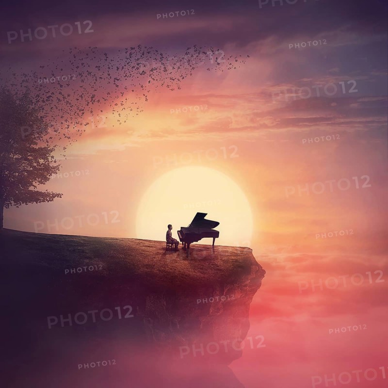 Musician sings and plays a piano song on the edge of a cliff over sunset sky