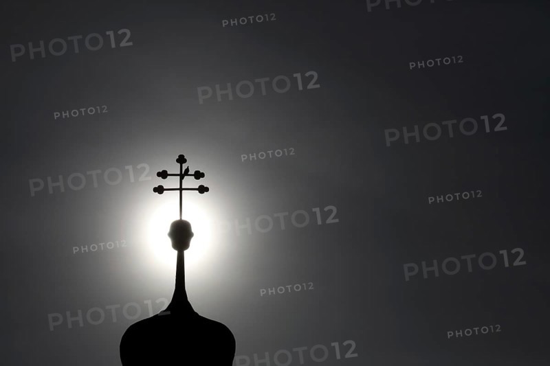 Double cross with dove on a church tower in backlight