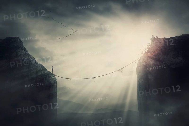 Person on the edge of precipice determined to overcome the obstacle by passing an old slackline bridge