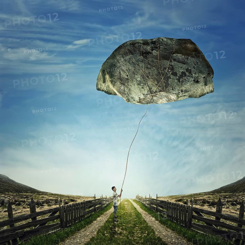 Surrealistic image as a young boy stand on a country road