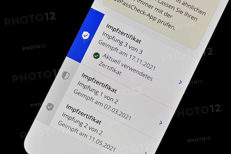 Symbolic photo App CovPass on smartphone with digital European vaccination certificate after third booster vaccination against Covid-19