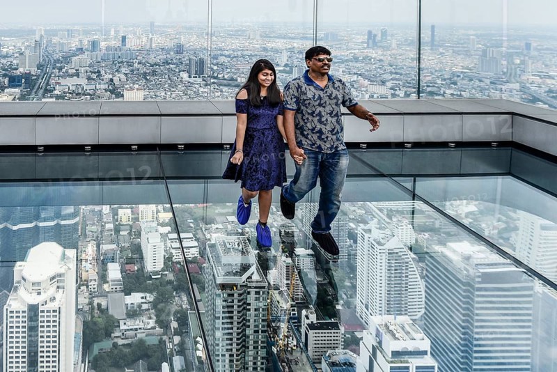 Tourists pose on the glass floor of Maha Nakhon Tower