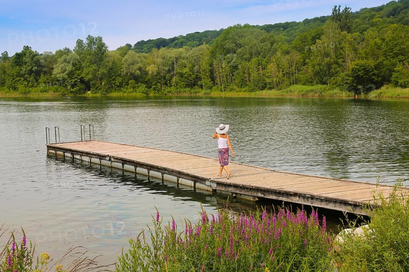 Woman in sun hat and skirt walking on jetty