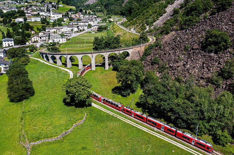 Aerial of a Train crossing the Brusio spiral viaduct